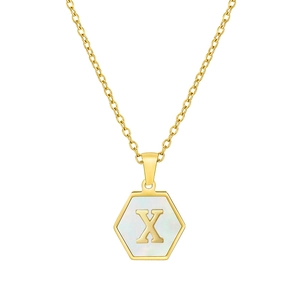 Macro shot of a hexagonal gold pendant with a mother of pearl base and a gold letter X