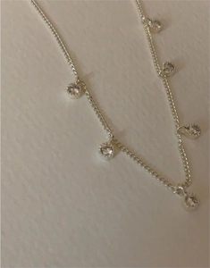 Detailed close-up of S925 silver necklace featuring five round zircon charms in claw settings