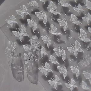 Detailed macro view of 3D embossed white butterfly nail stickers with silver glitter