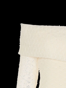 Detail of off-white off-shoulder knit top showing the 3D granular fabric texture