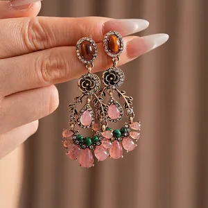 Vintage gold earrings with rhinestone flowers and pink water drop tassels on model