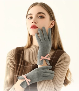 Gros plan de gants thermiques gris ornés d'un délicat nœud rose sur le poignet