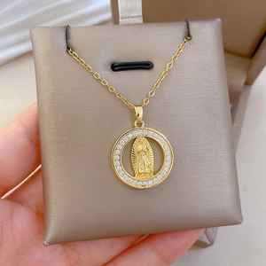 Detailed view of a gold portrait medallion necklace with sparkling crystals on display card