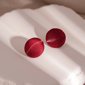 Detailed view of round dark red fabric wrapped earrings with vintage satin texture finish
