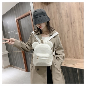 White plush backpack with cute bear ears worn by a model in a casual indoor setting