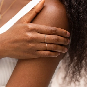 Close-up of minimalist gold chain ring and slim band on hand in natural light