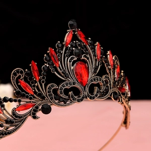 Detail of baroque vintage black crown featuring red teardrop gemstone and antique gold metal