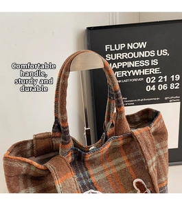 Detailed close-up of wool plaid tote bag with cute bear patch and sturdy brown handle