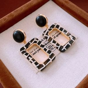 Detail view of retro geometric resin earrings with black and white checkered pattern finish