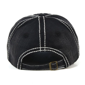 Detail of adjustable metal buckle and contrast stitching on black denim baseball cap