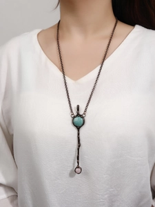 Detail of vintage bronze necklace featuring green amazonite and pink quartz stone pendants
