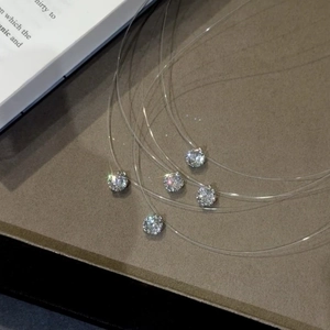 Dettaglio di collane invisibili in nylon con pendenti in zirconia cubica scintillanti