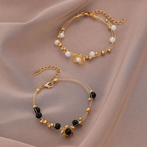 Detalle de pulseras de perlas vintage con flores doradas en elegante satén de champán
