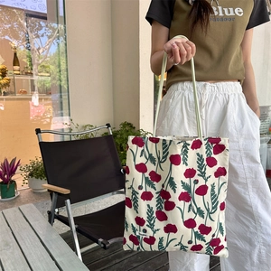 Détail du sac cabas en toile à fleurs rouges avec l'étiquette de marque Sezakka
