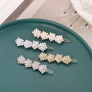 Set of four Korean style floral hair clips with rhinestones and pearls on a green plate