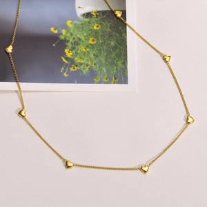 Detailed view of multiple 18K gold plated heart pendants on a minimalist chain