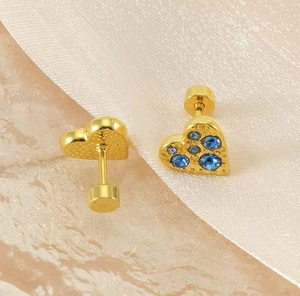 Detailed macro view of gold heart stud earring with blue stones and screw back closure