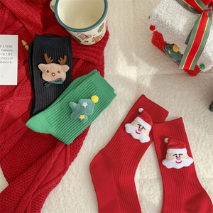 Detail of festive Christmas crew socks with 3D plush deer and Santa Claus characters
