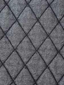 Detailed macro view of diamond quilted washed denim fabric with grey textured stitching