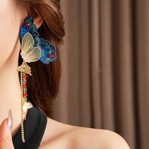 Detail von Vintage Schmetterling Ohrring mit blauer Stickerei, Goldfransen und roten Steinen