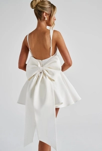 Detailed back view of a white satin mini dress featuring a large elegant bow decoration