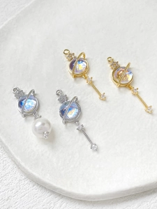 Detailed view of 14k gold-filled planet charms with cat-eye stones and zircon inlays