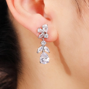 Macro detail of silver floral drop earrings with pear-cut crystals on a model