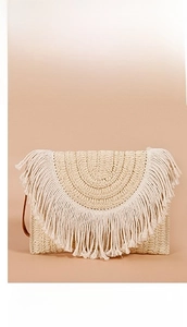 Close-up of woven straw envelope clutch bag featuring beige fringe and brown wrist strap