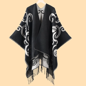 Detail of black and grey paisley poncho with thick cashmere-like fabric and fringe trim