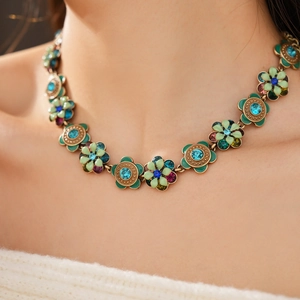 Detail view of vintage flower necklace with green enamel and colorful crystal accents
