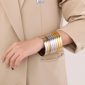 Close-up of gold, silver, and rose gold stainless steel bangles worn by a model
