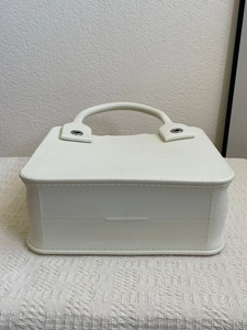 Detail of white EVA tote bag featuring a sturdy handle and metallic rivet accents
