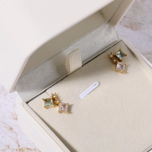 Detail showing gold-plated birthstone earrings with blue square-cut cubic zirconia gems