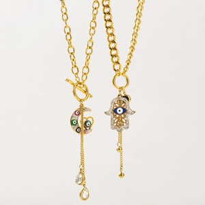 Détail des breloques main de Hamsa et lune avec émail œil bleu et pompons dorés