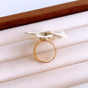 Macro detail of a 3D white flower ring with gold metal band in a beige velvet gift box