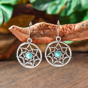 Detail of vintage bohemian drop earrings with turquoise beads on a rustic wooden branch