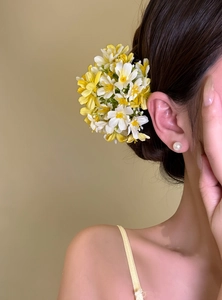 Yellow and white floral hair clip shown as side accessory on model for beach vacation style