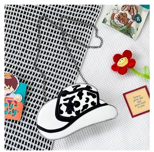Detail of cowboy hat-shaped crossbody bag with cow print pattern and star patch