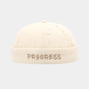 Dettaglio del cappello docker crema con ricamo PROGRESS e design vintage consumato