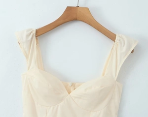 Detail showing the cream off-shoulder dress with a structured sweetheart neckline and zipper