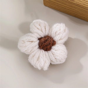 Macro shot of handcrafted white knitted flower with brown center for brooch DIY