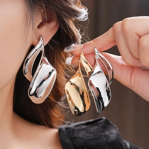 Close-up of irregular twisted leaf earrings in polished gold and silver liquid metal finish