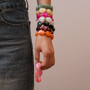 Close-up of colorful resin bead bracelets with gold spacers worn as a layered stack