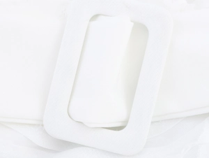 Macro detail of the white fabric-wrapped rectangular belt buckle on the long dress