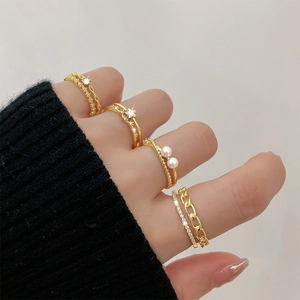 Close-up of four gold-plated rings with stars, pearls and chains on a female hand