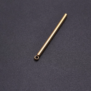 Macro shot of polished gold cylinder pendant with small loop on matte black background