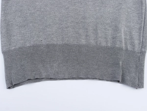 Détail du t-shirt en tricot gris montrant l'ourlet côtelé et la texture du tissu