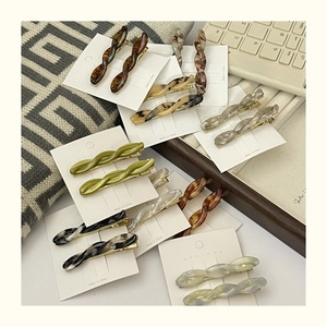 Macro detail of twisted acetate hair clips in marble and tortoiseshell patterns