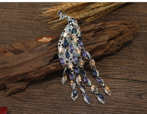 Detailed close-up of a peacock brooch with multi-colored crystals and tassel accents