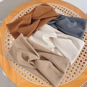 Détail de quatre bandeaux noués en marron, gris, beige et blanc sur du rotin